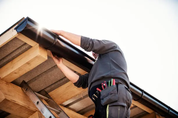 Pose d'une gouttière sous un débord de toit en bois